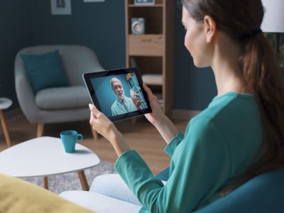 Woman having a video call with her doctor using a digital tablet, telemedicine concept