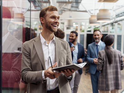 Smiling handsome businessman standing in office and looking at side. High quality photo